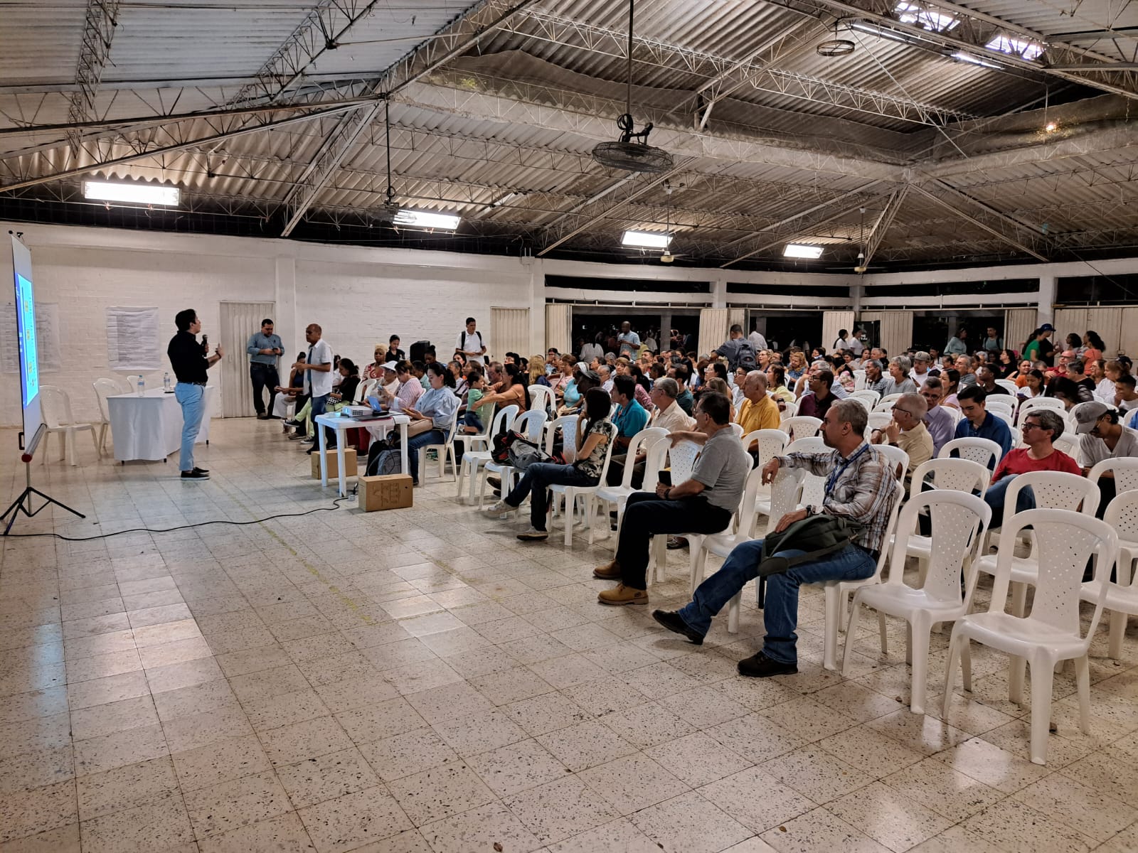 Grupo de personas reunidas en un salon escuchando la conferencia acerca del Plan de desarrollo